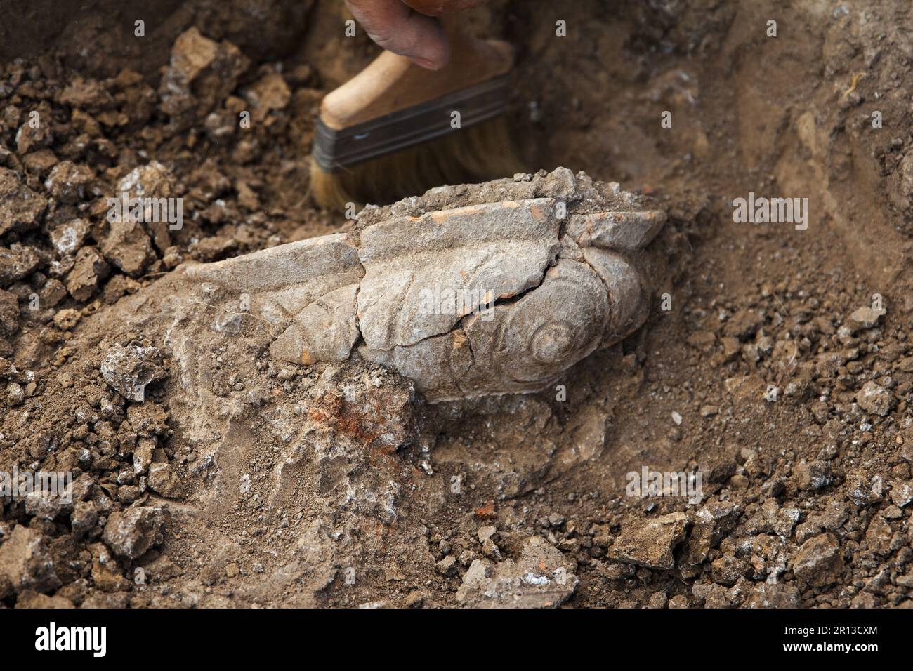 Scavi archeologici, archeologo di lavoro, scavare un antico manufatto in argilla con attrezzi speciali, spazzolare nel terreno Foto Stock