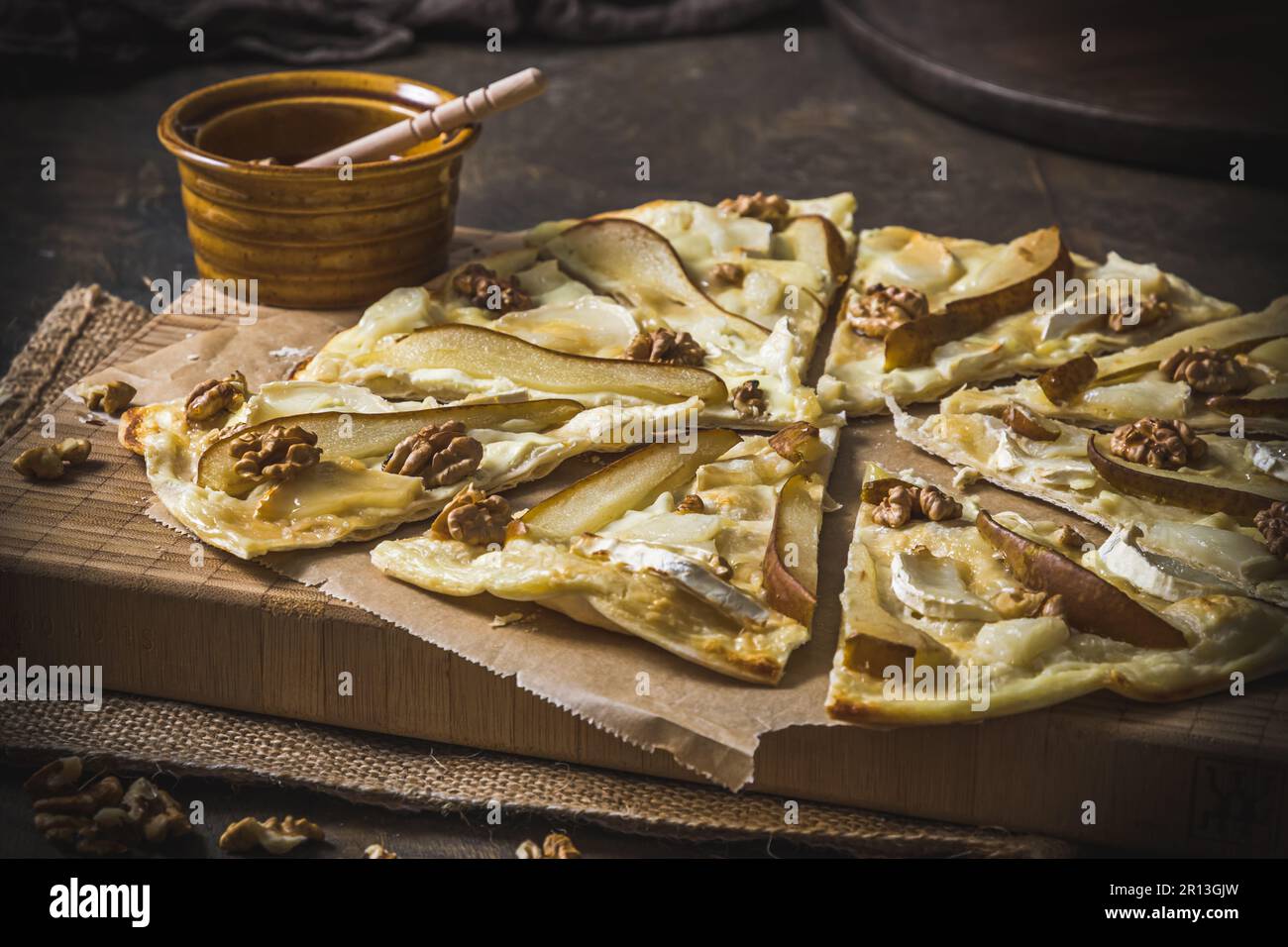 Tarte flambee con pera, formaggio di capra, miele e noci su fondo di legno rustico scuro Foto Stock
