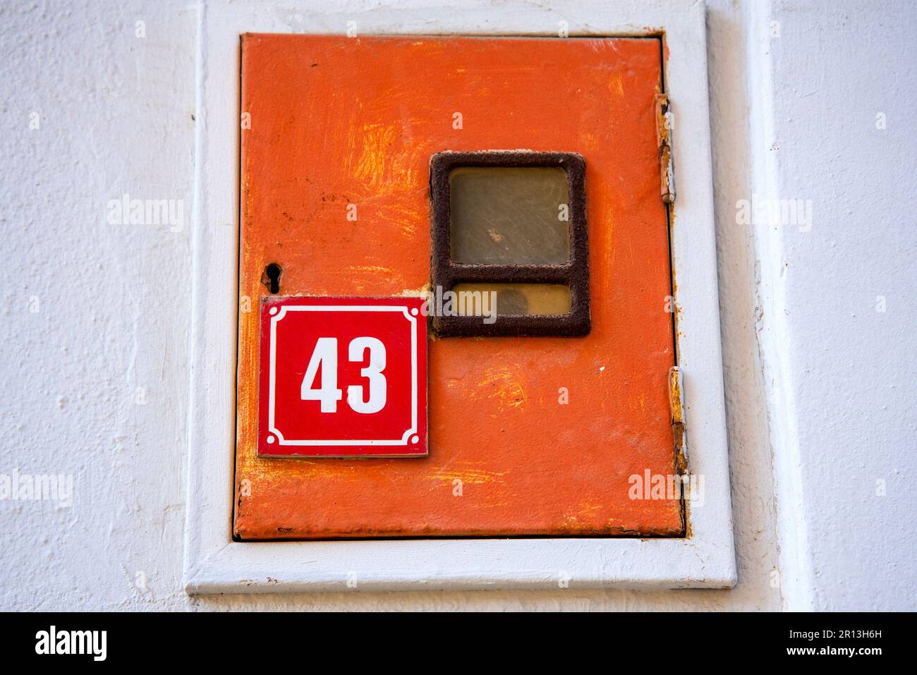 Una targhetta rossa con il numero civico che indica il numero 43. Un piccolo armadio da incasso. Foto Stock