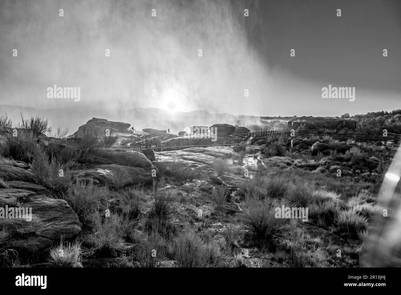 Alba attraverso lo spruzzo di una cascata di Augrabies Falls. Passerelle sono visibili. Monocromatico Foto Stock