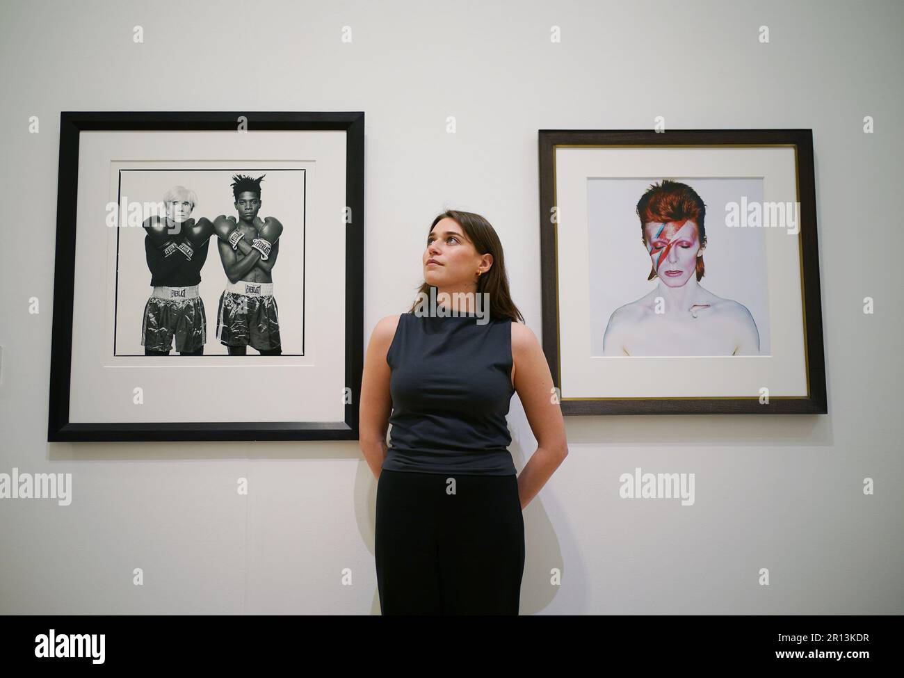 Un membro del personale della galleria posa accanto alle fotografie di (a sinistra) Michael Halsband, Andy Warhol + Jean-Michel Basquiat #143, New York City, 10th luglio 1985, con una stima di £20.000-30.000, E Brian Duffy, David Bowie, 1973 anni, con una stima di £ 7.000-9.000, in mostra a Phillips, Londra, durante una telefonata fotografica per una collezione privata di opere di fotografi del 20th e del 21st ° secolo, prima di essere offerti per la vendita dalla casa d'aste. Data immagine: Giovedì 11 maggio 2023. Foto Stock