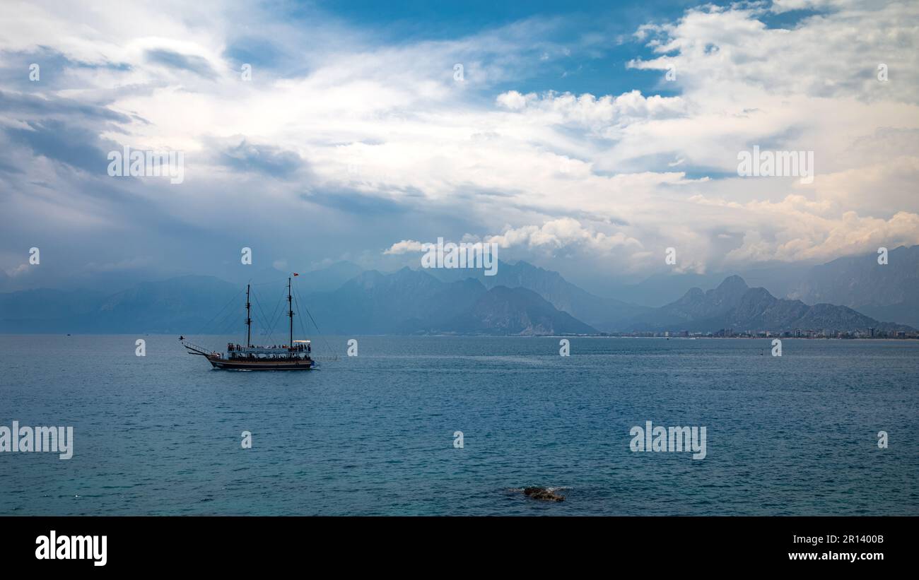 Una nave pirata turistica naviga attraverso le acque calme del Mar Mediterraneo nella baia al largo di Antalya, Turchia (Turkiye). Il profilo nebuloso del Toro m Foto Stock