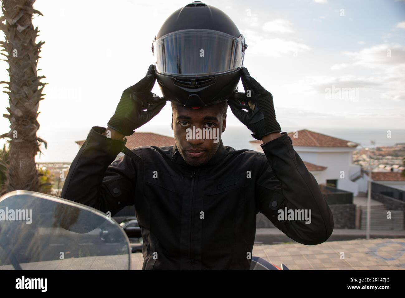 Primo piano di un ciclista afroamericano che si prepara a cavalcare indossando il casco. Concetto di sicurezza stradale Foto Stock