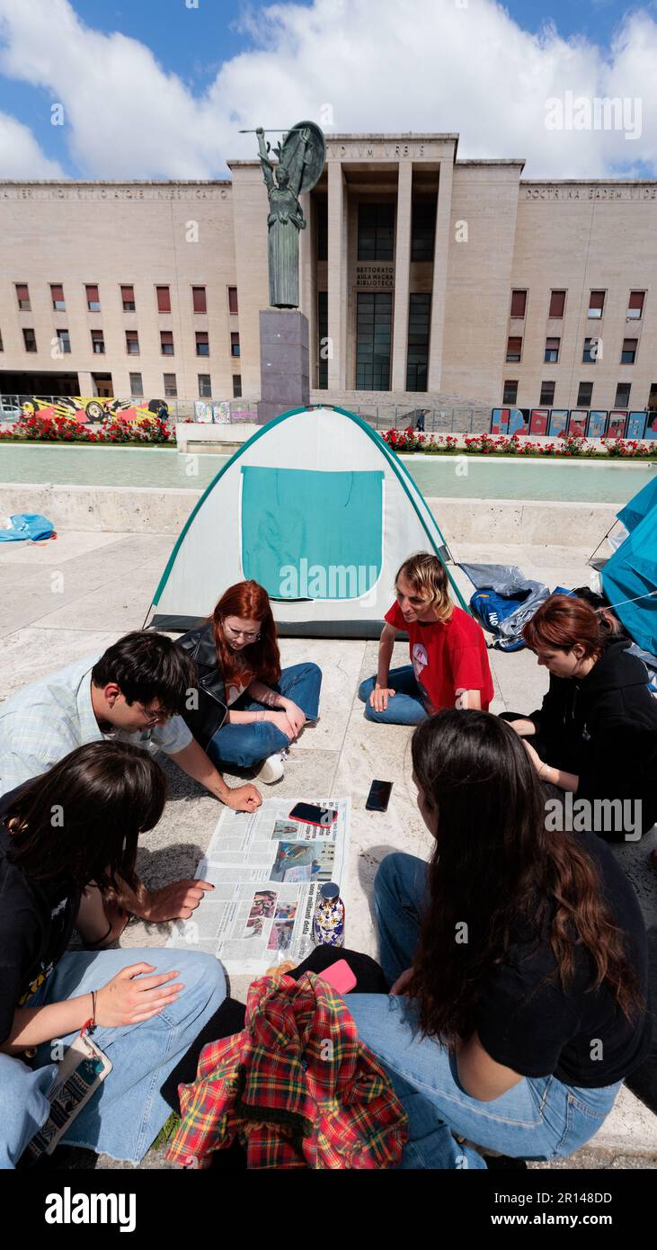 Un gruppo di studenti si impegnano in una discussione durante una protesta per l'aumento dei costi di affitto presso l'Università Sapienza di Roma, con l'iconica statua di Minerva Foto Stock