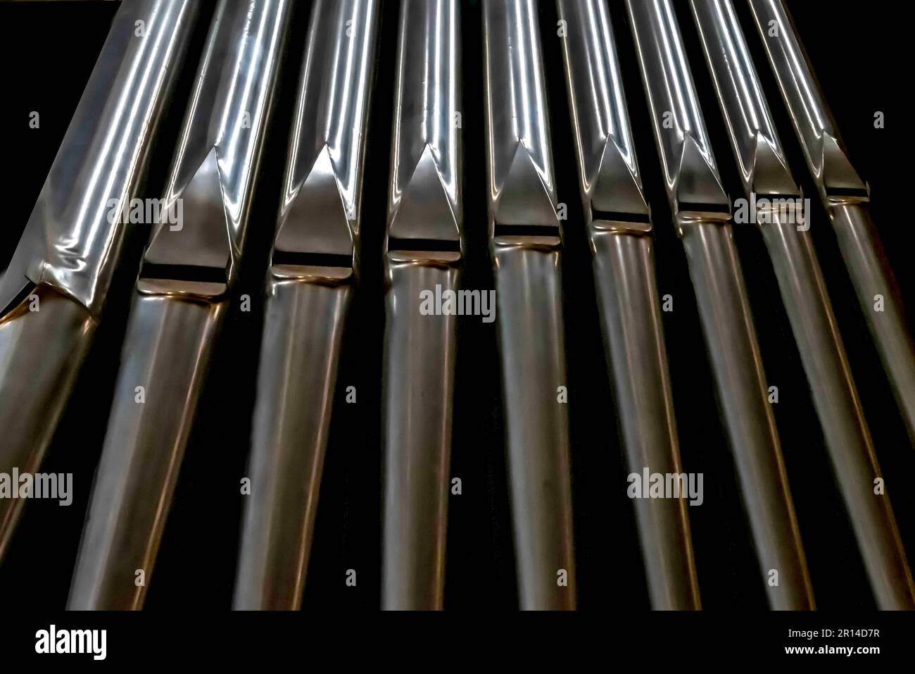 Primo piano di diversi tubi metallici in una linea su sfondo nero Foto Stock