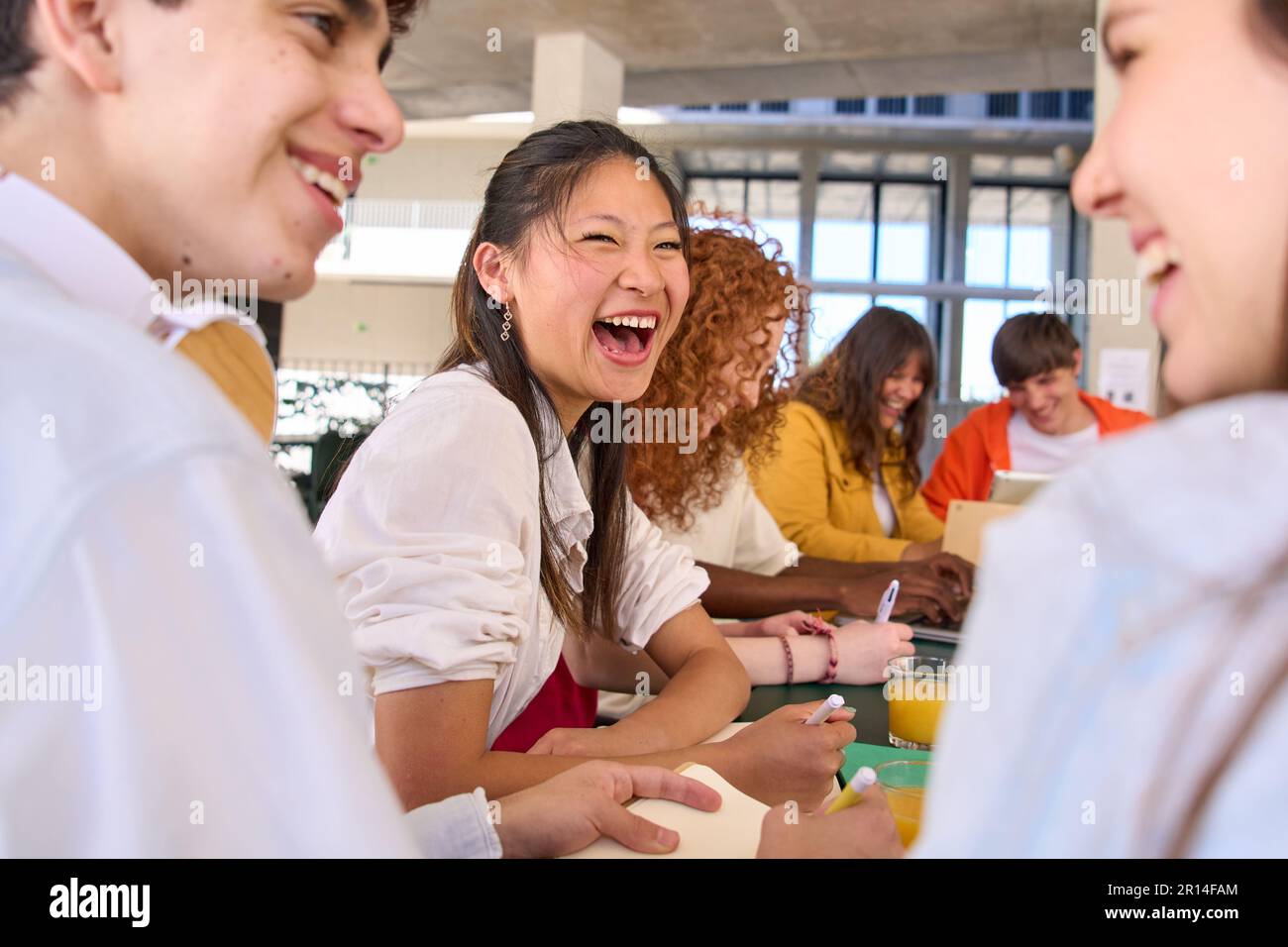 Gruppo di giovani studenti caucasici sorridenti che parlano mentre studiano nella caffetteria del campus universitario. Foto Stock