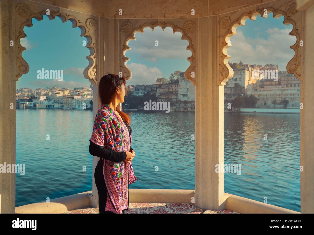 Donna asiatica godere la vista dalla finestra arco apertura con Udaipur città sul retro, Udaipur, India Foto Stock