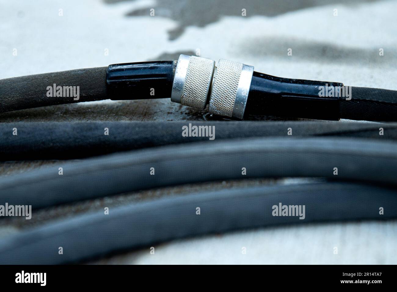 Primo piano del collegamento del tubo flessibile da giardino nero intrecciato su cemento Foto Stock