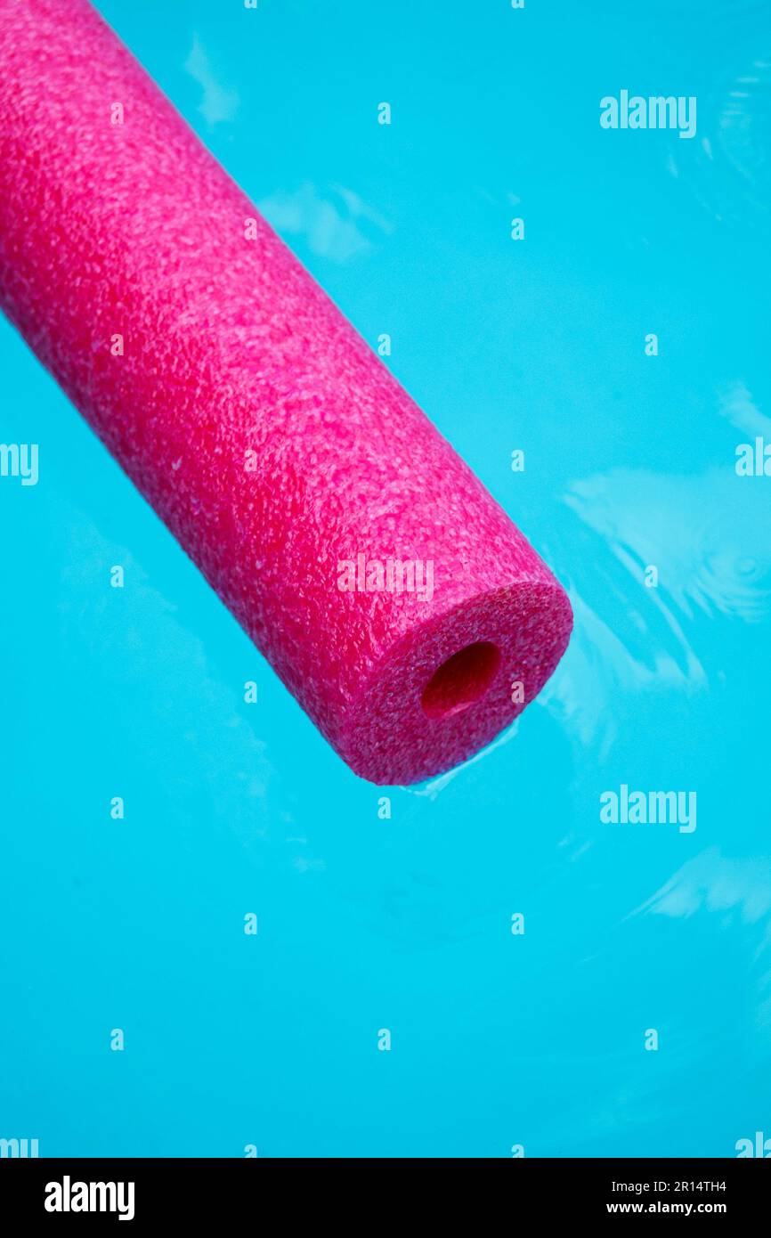 noodle rosa della piscina che galleggia sull'acqua blu Foto Stock