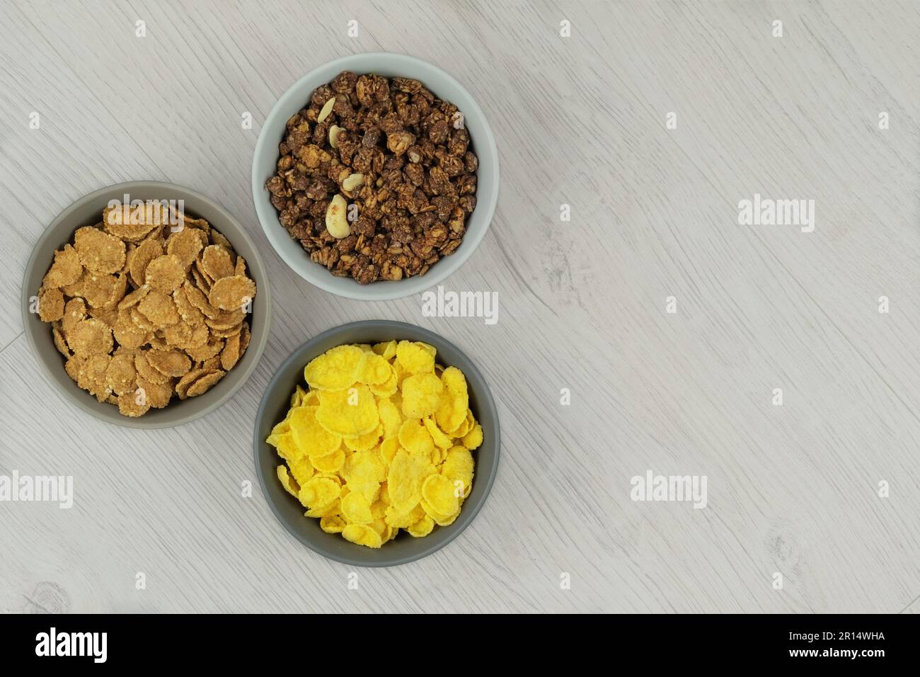 Cereali da colazione in ciotole su uno sfondo di legno chiaro. Fast food. Spazio per il testo. Vista dall'alto. Foto Stock