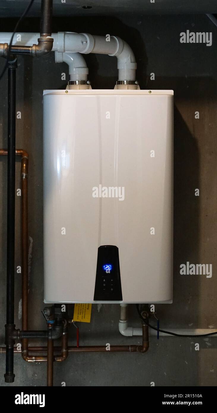 Riscaldatore di acqua calda Tankless installato in una stanza della caldaia della casa. Foto Stock
