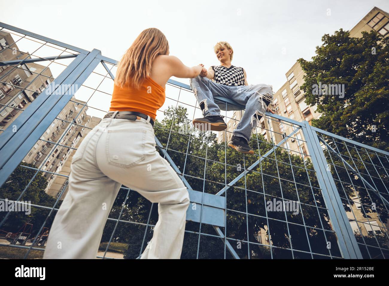 Un adolescente ribelle che si arrampica sulla recinzione su una strada. Foto Stock