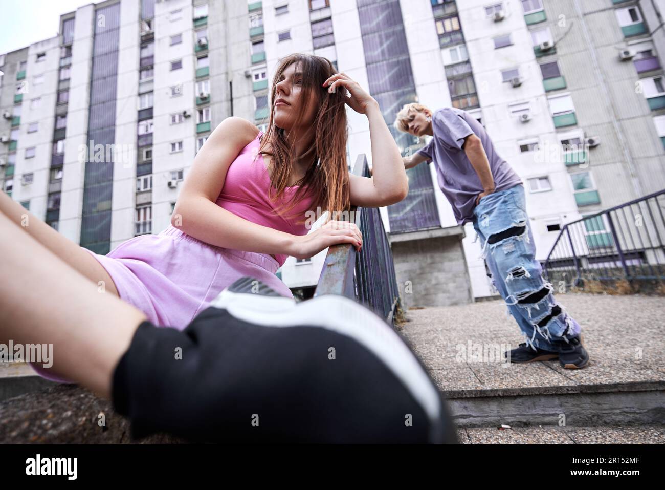 Una ragazza adolescente in posa in città esterno mentre il suo ragazzo in piedi in background. Foto Stock