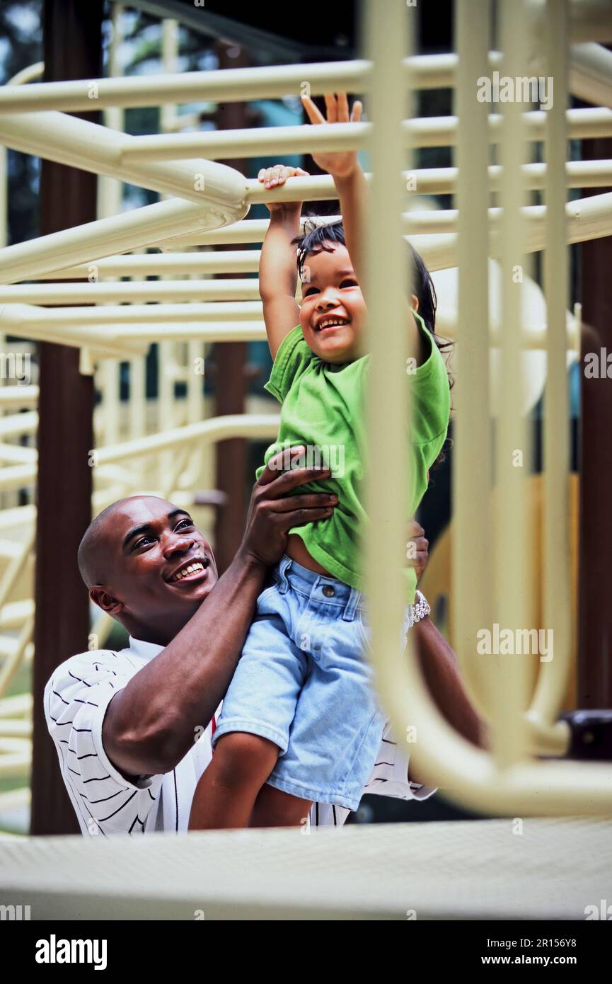 Un padre afroamericano che aiuta sua figlia ad aggiungere un parco giochi Foto Stock