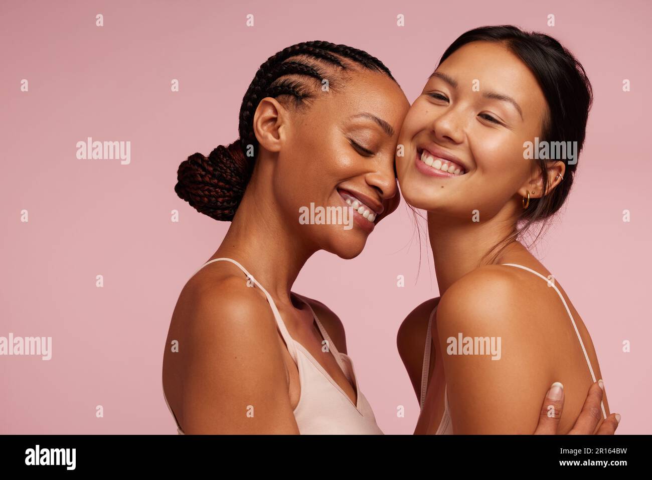 Due femmine con pelle sana in piedi insieme e sorridente. Donne attraenti con pelle impeccabile sorridendo insieme. Foto Stock