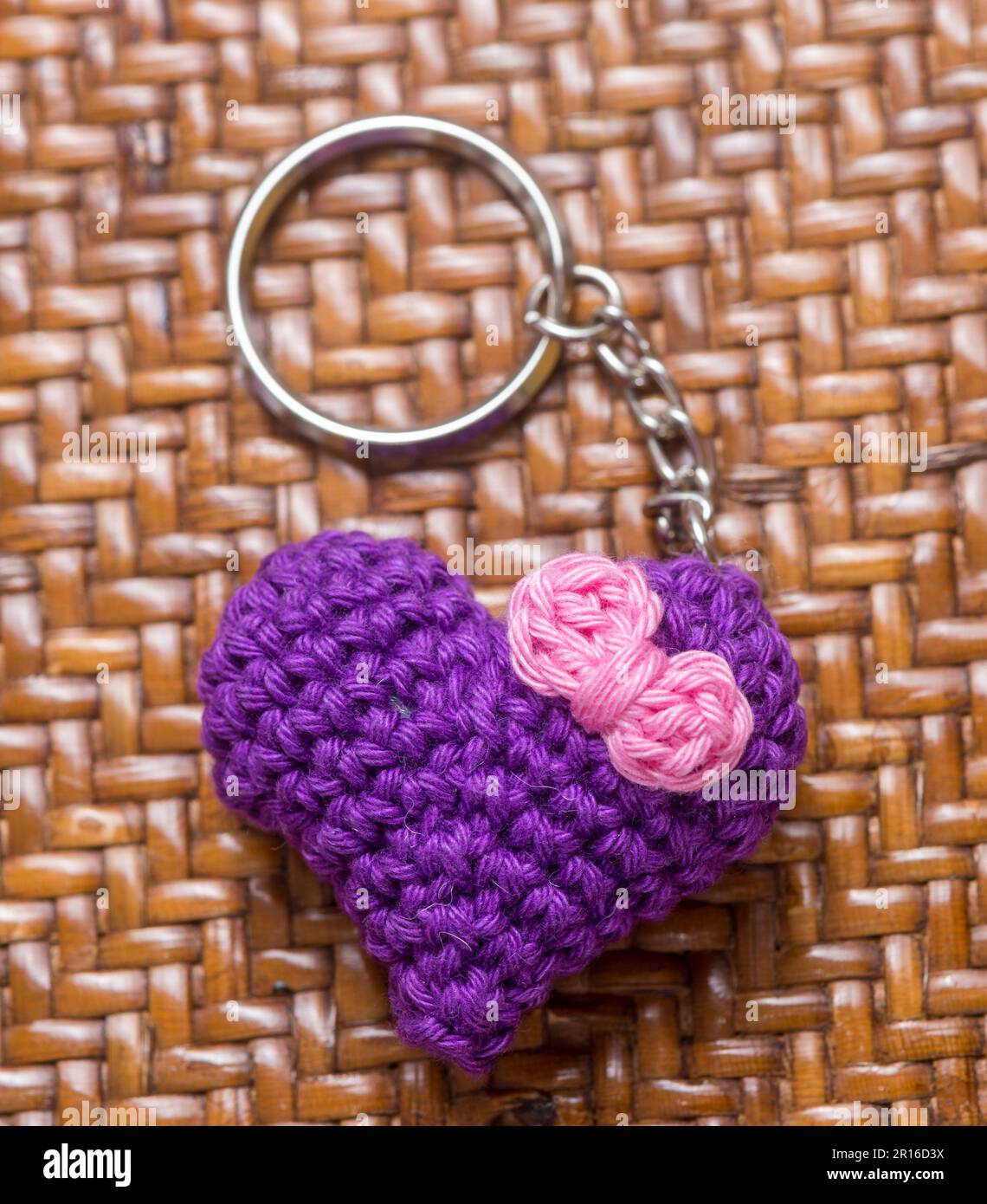 Portachiavi a forma di cuore viola con un solo motivo a crocheto su uno sfondo testurizzato Foto Stock