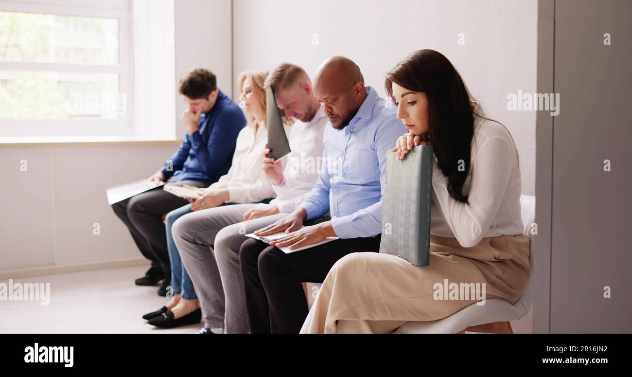 La gente di affari sono annoiarsi mentre è seduto su una sedia in attesa per il colloquio di lavoro in ufficio Foto Stock