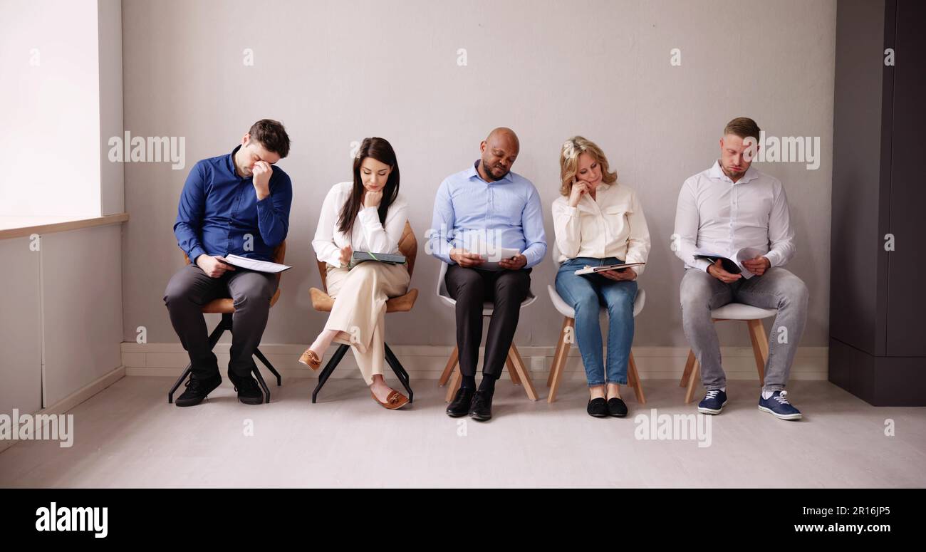 La gente di affari sono annoiarsi mentre è seduto su una sedia in attesa per il colloquio di lavoro in ufficio Foto Stock