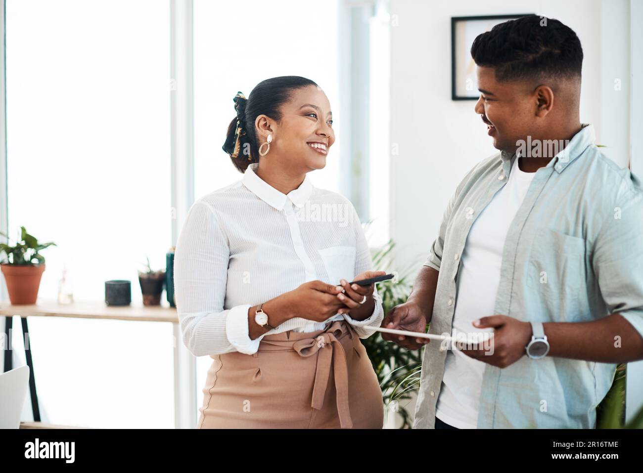Ottenere parlare di questioni che lo fanno accadere. un giovane uomo d'affari e una donna d'affari che utilizzano dispositivi wireless durante una discussione in un ufficio moderno. Foto Stock