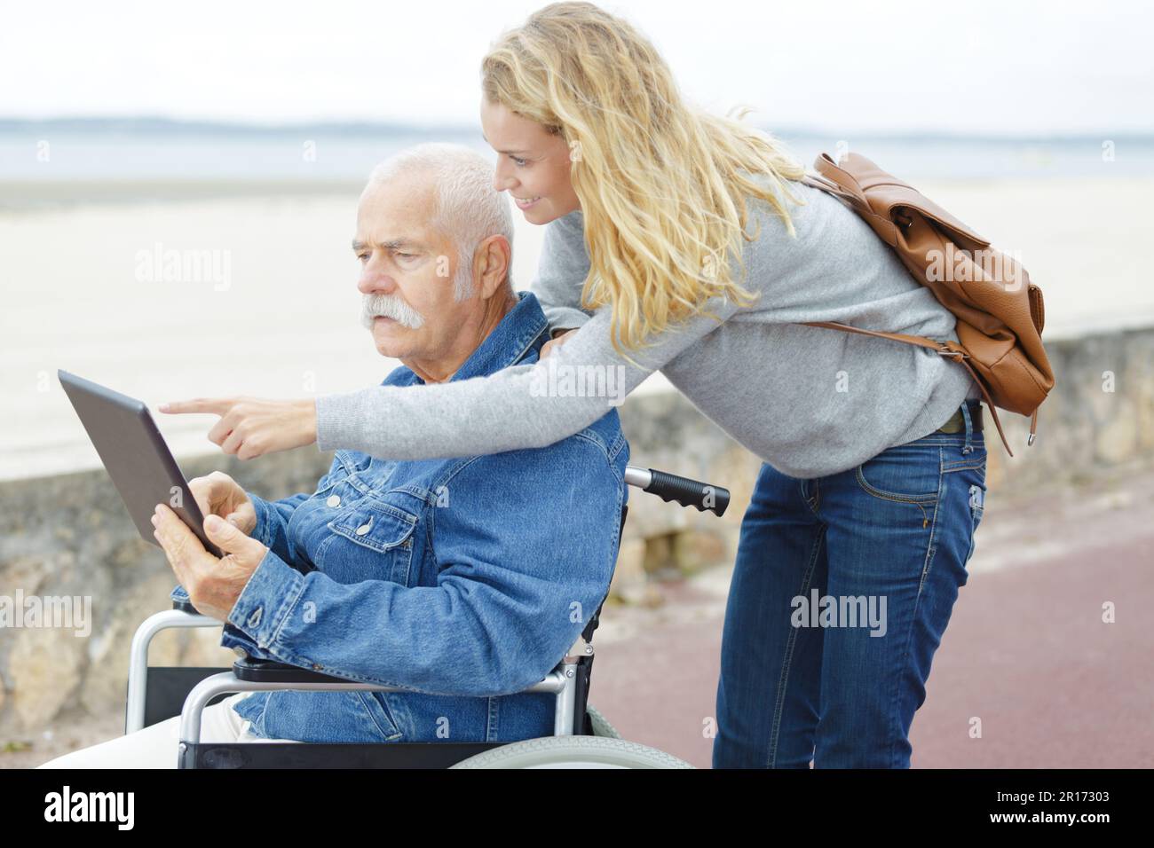 uomo disabile con sua figlia che usa un tablet al parco Foto Stock