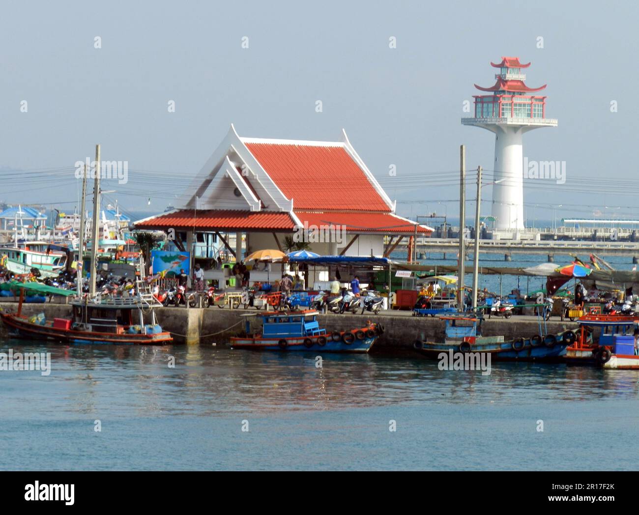 Thailandia, Chonburi, Ko si Chang Island: Vivace molo di Tha Lang con barche da pesca e noleggio scooter, e la torre di osservazione sullo sfondo. Foto Stock
