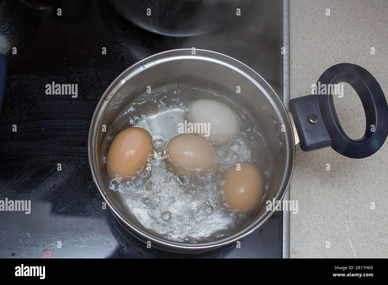 uova bollite in una padella su una piastra elettrica al mattino Foto Stock
