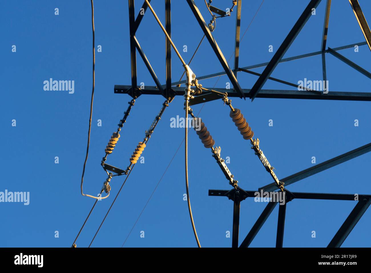 Albero in acciaio di un polo elettrico ad alta tensione contro il cielo blu. Linea di trasmissione di potenza. Primo piano Foto Stock