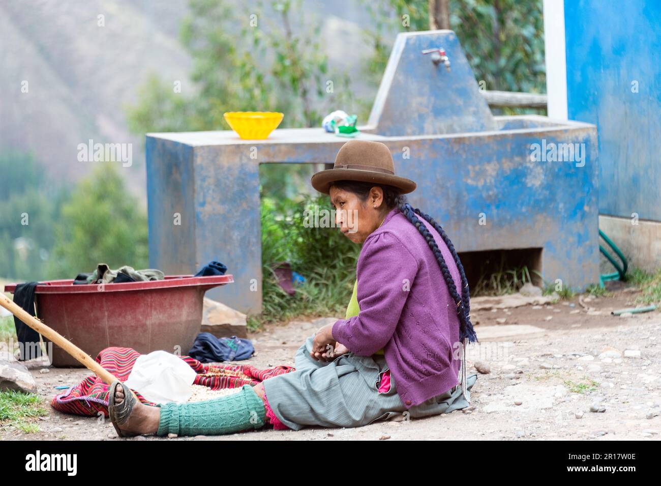 Donna peruviana seduta sul pavimento con vestiti da lavare, Pisac, Perù Foto Stock
