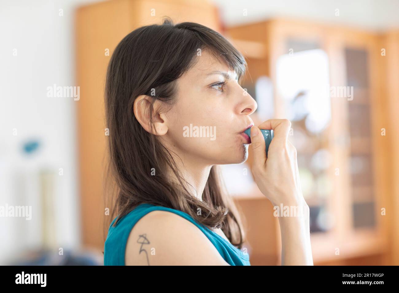 donna che usa spray per asma a casa Foto Stock