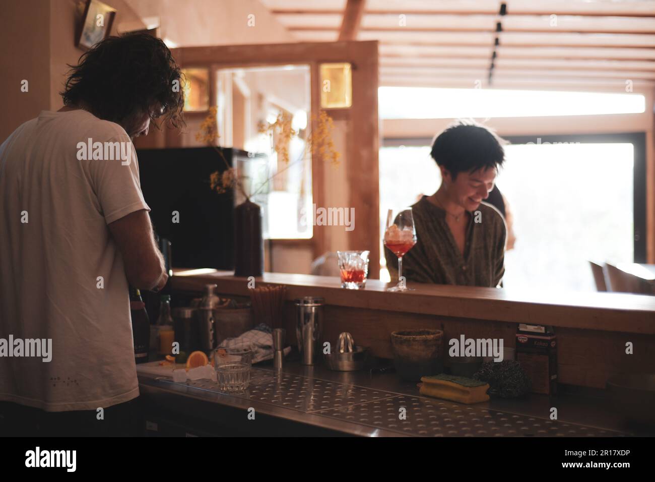 il barista chiacchiera con il cliente mentre fa un cocktail nel caffè naturale Foto Stock
