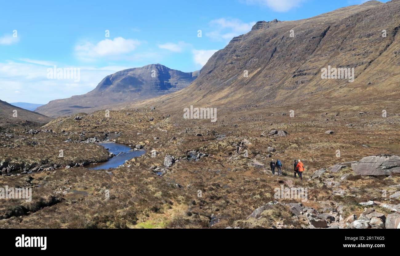 Highlands scozzesi: Camminatori nella valle di Coire MhicNobaill, vicino a Torridon. Mostra le spettacolari vette di Beinn Alligin sullo sfondo. Foto Stock