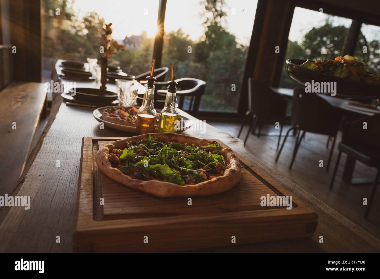 pizza biologica cotta a legna su tavola di legno con sole al tramonto Foto Stock