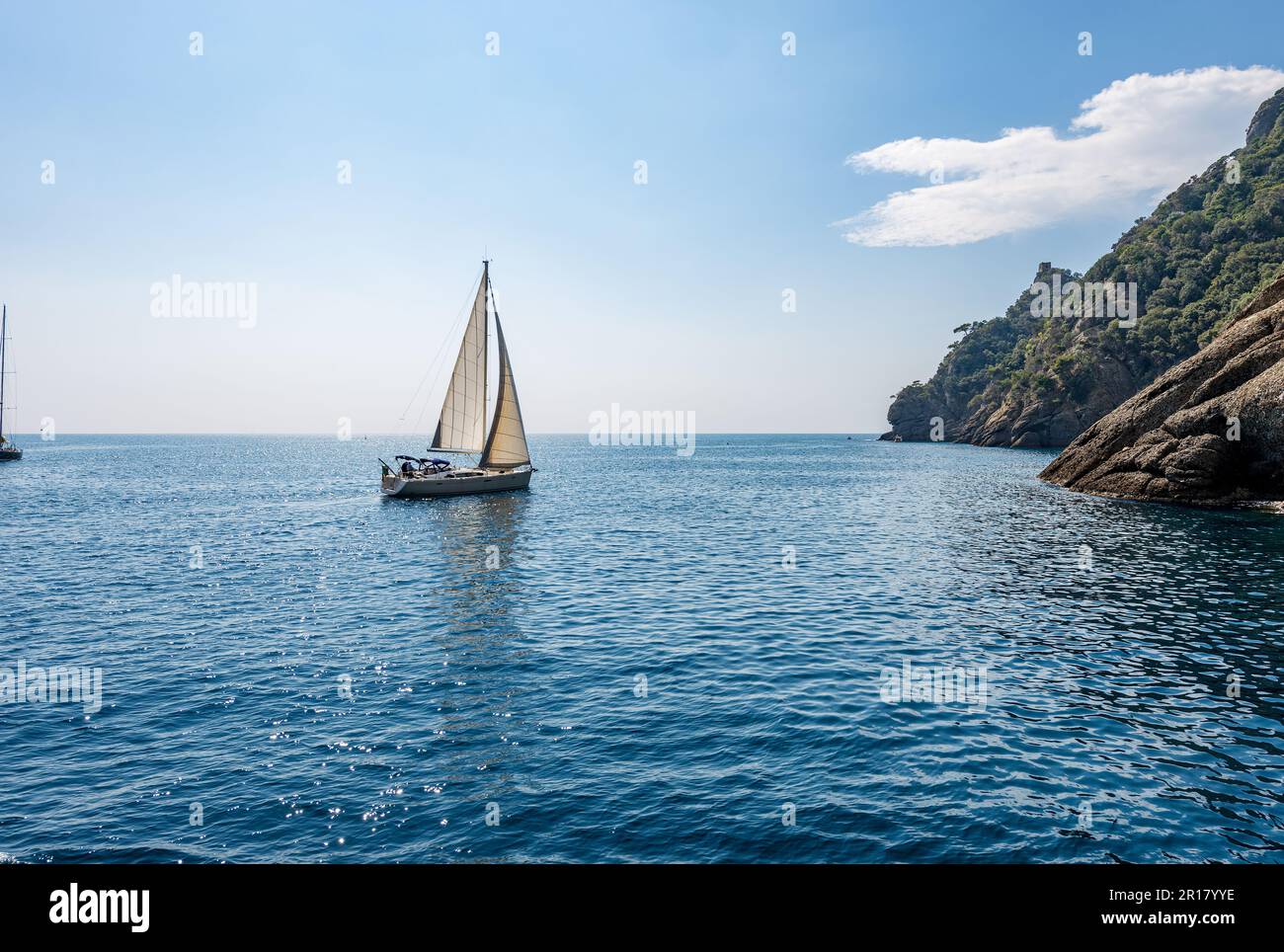 Barca a vela bianca in movimento nell'azzurro mar Mediterraneo (Mar Ligure) di fronte alla baia di San Fruttuoso tra Portofino e Camogli, Liguria. Foto Stock