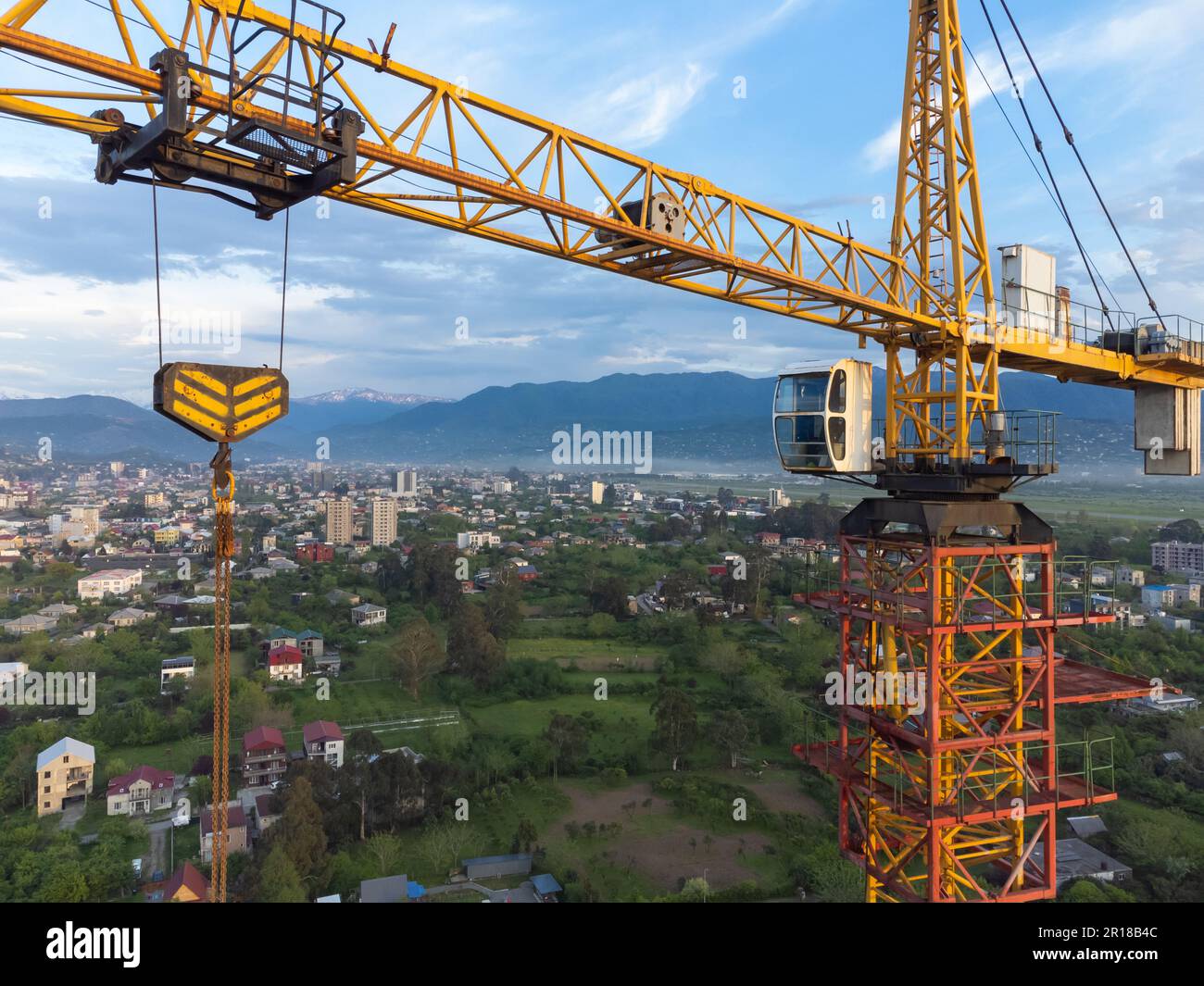 Vista ravvicinata da un drone di una cabina gru da cantiere sullo sfondo di splendide montagne e cielo. Concetto di costruzione Foto Stock