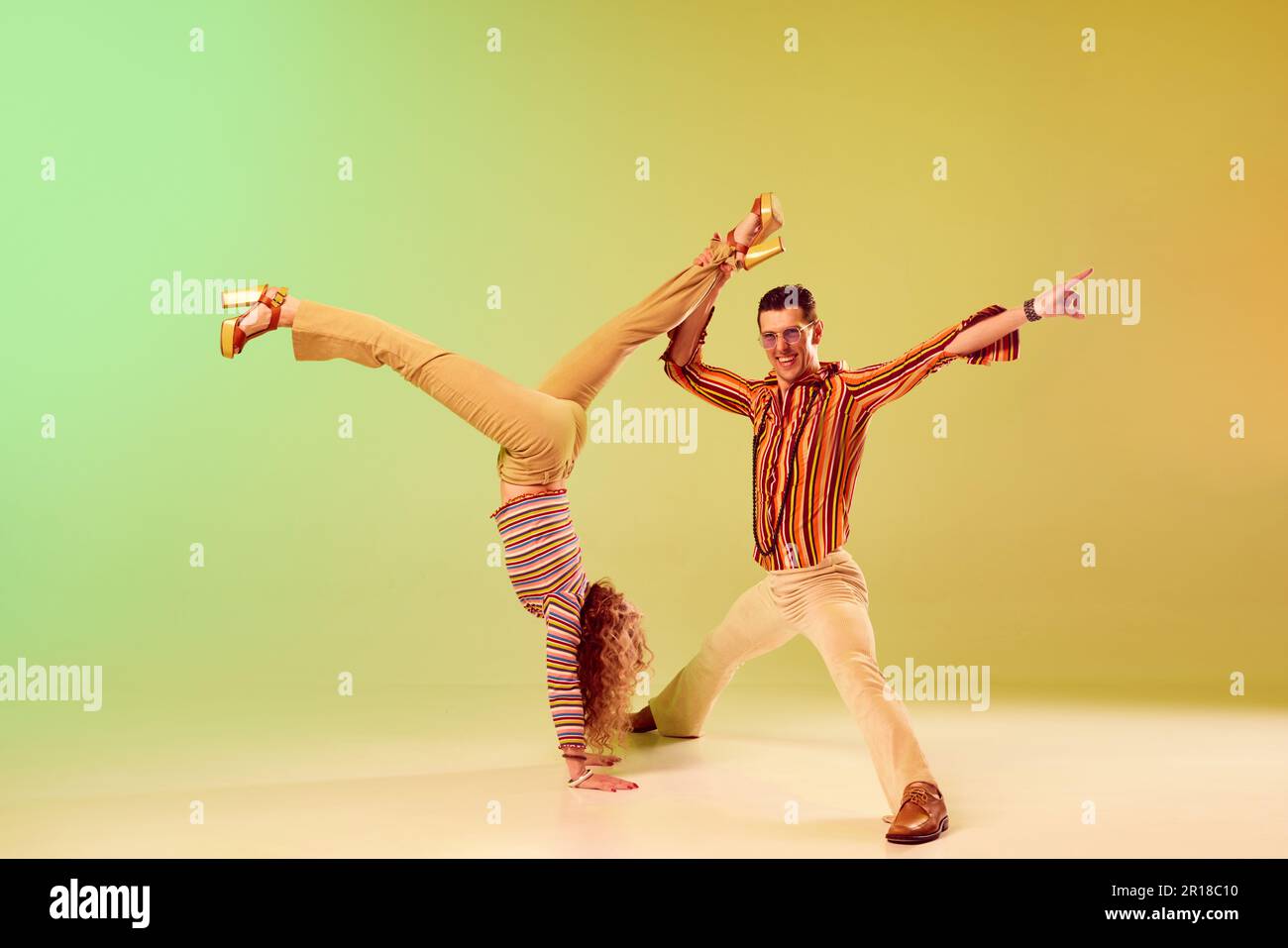 Coreografia. Due persone di talento, uomo e donna autistici in vintage vestiti che ballano contro gradiente verde sfondo giallo Foto Stock