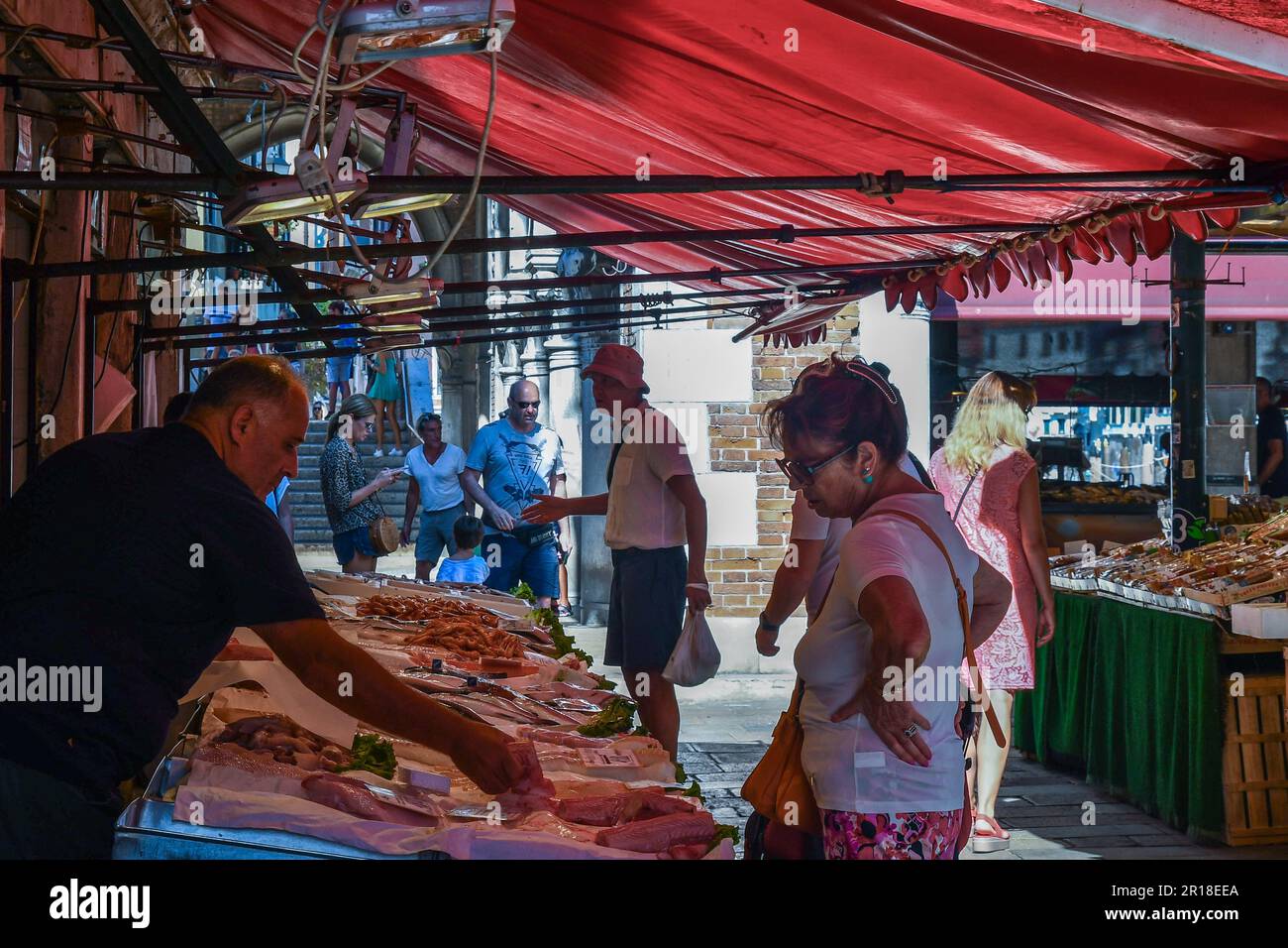 Donna che acquista pesce fresco da un combattente al mercato di Rialto di campo della Pescaria in estate, Venezia, Veneto, Italia Foto Stock