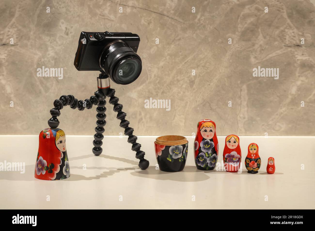 Una piccola fotocamera digitale nera che gioca con le bambole Matryoshka Foto Stock