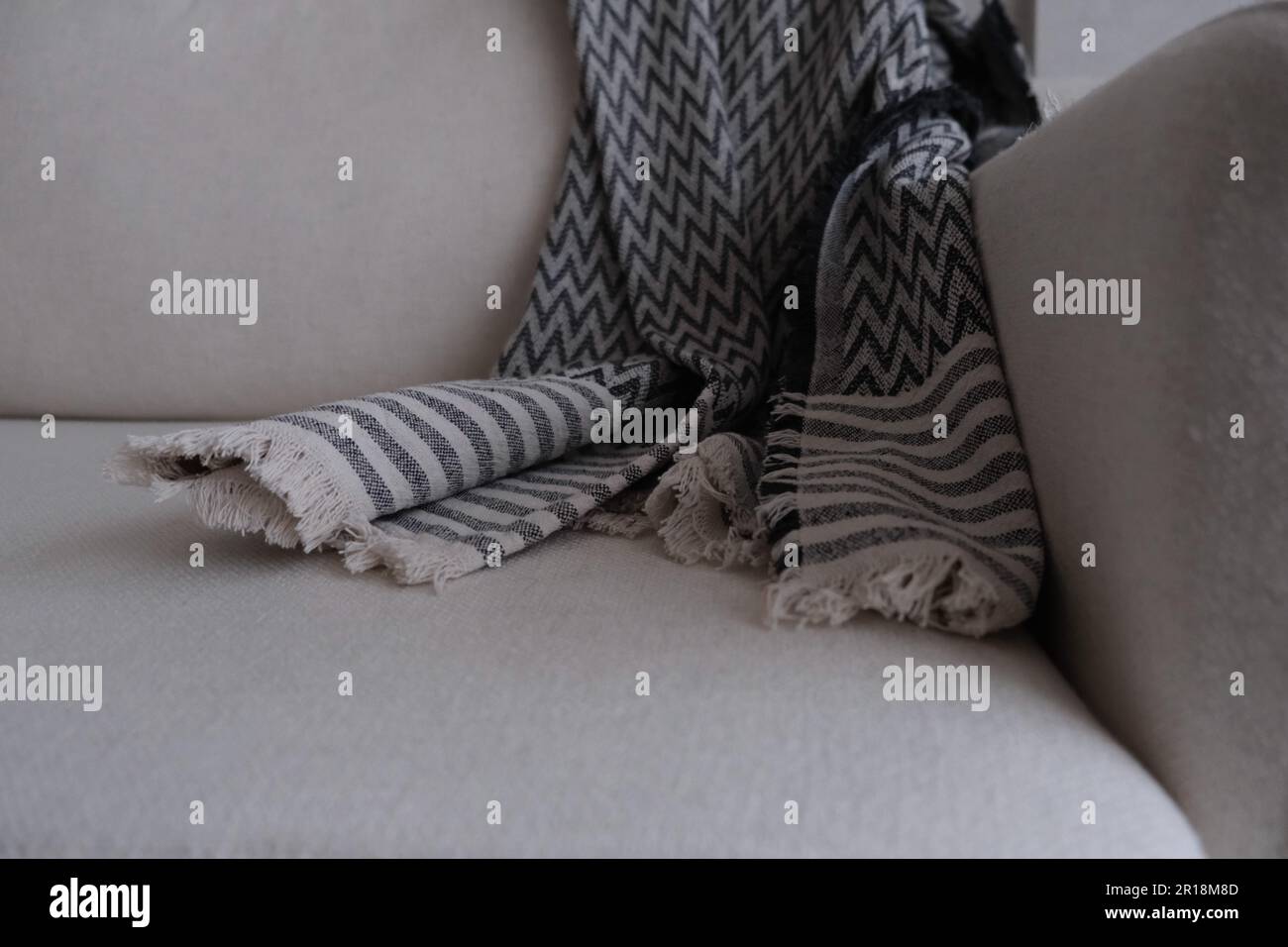 Divano bianco con una coperta a zig zag aperta. Accogliente idea di foto del concetto di soggiorno. Foto Stock