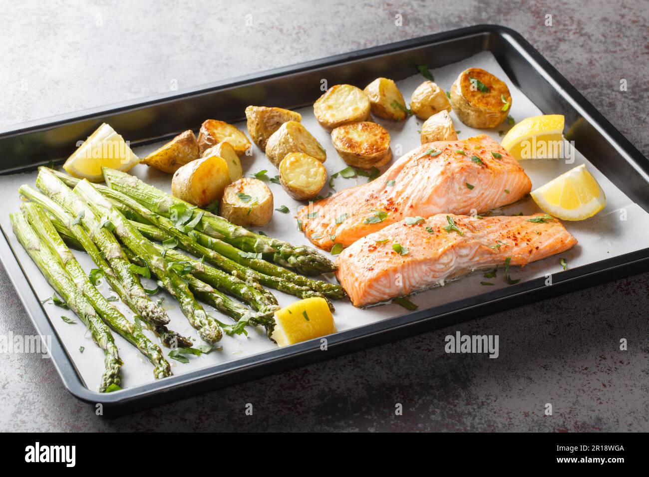 Dieta cibo filetto di salmone cotto con asparagi e patate novelle primo piano in una teglia da forno sul tavolo. Orizzontale Foto Stock