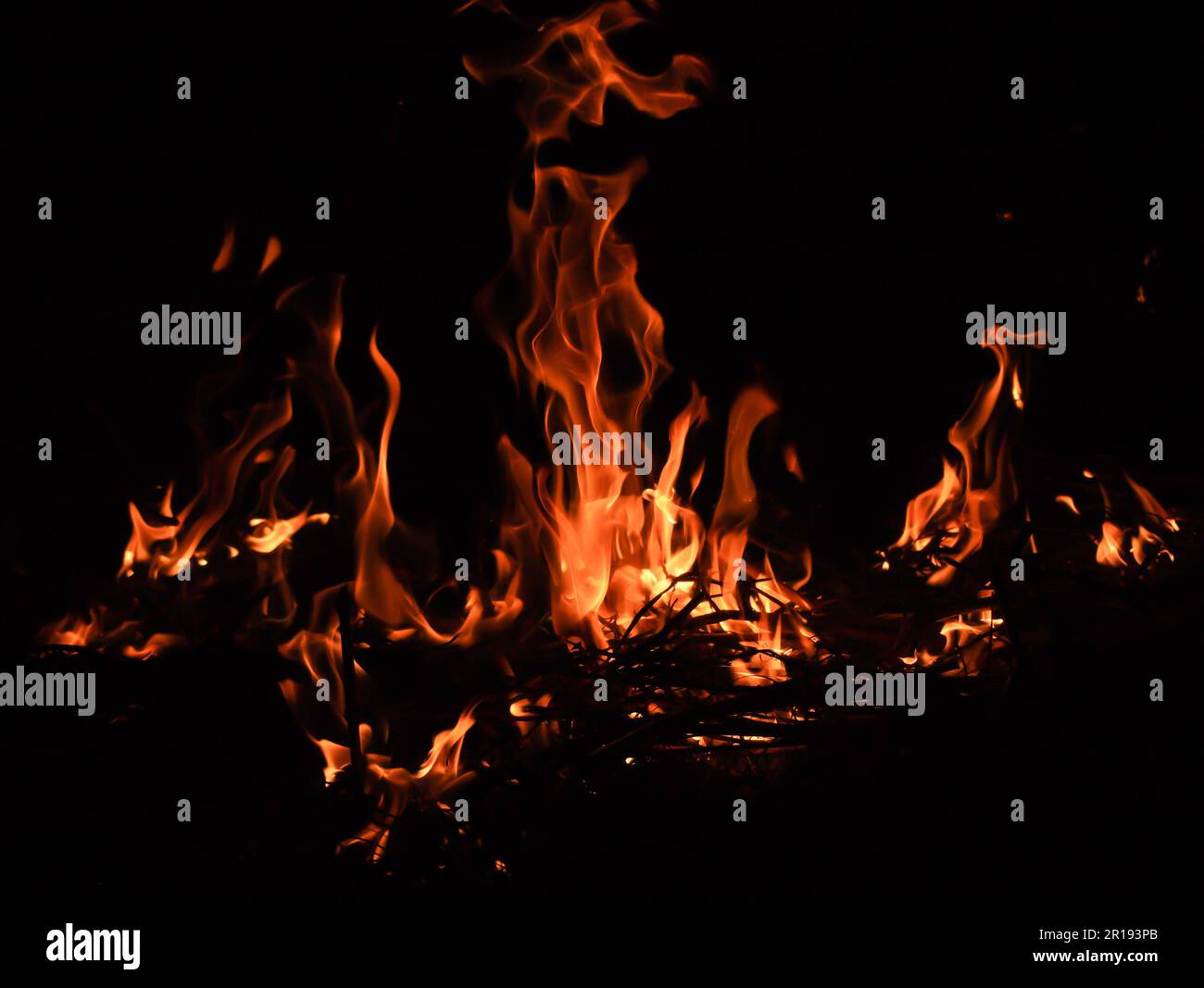 Fiamma di fuoco con scintille calde di colore rosso che bruciano isolate su fondo nero. La fiamma e il backgroud nero creano texture interessanti Foto Stock
