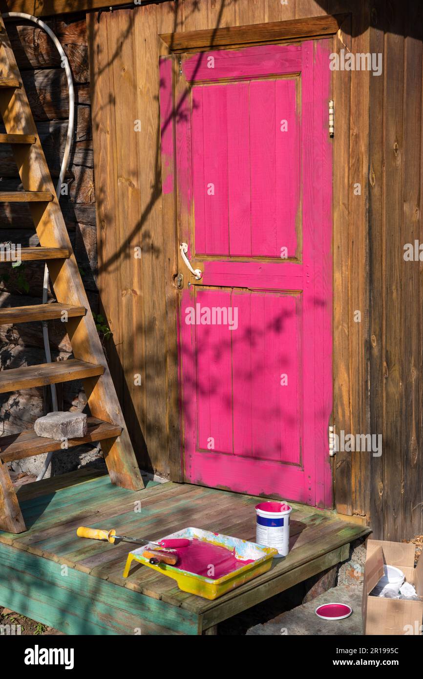 la porta di una casa in legno dipinta in un chiaro colore viola, rosa, fucsia. casa di campagna, vita di campagna Foto Stock