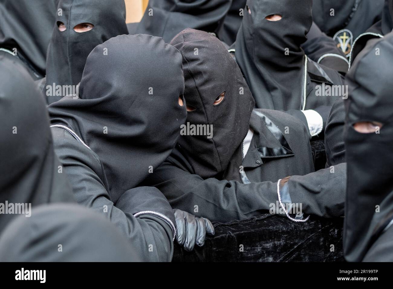 I membri dell'Cofradía del Cristo del Gran Poder chiacchierano durante una processione di Semana Santa a Leon, Spagna Foto Stock
