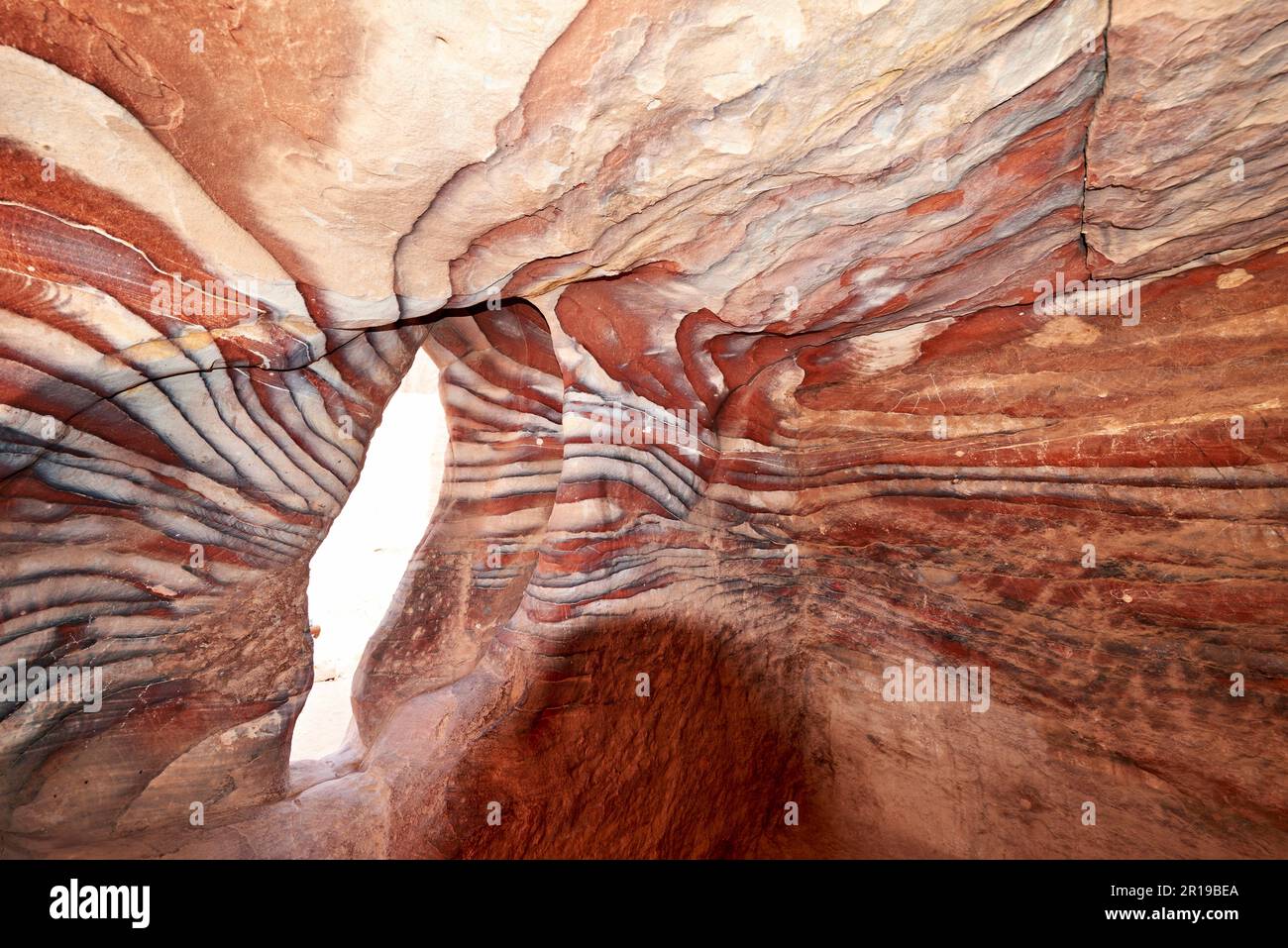 Giordania. Sito archeologico di Petra. Rocce rosse colorate nella grotta Foto Stock