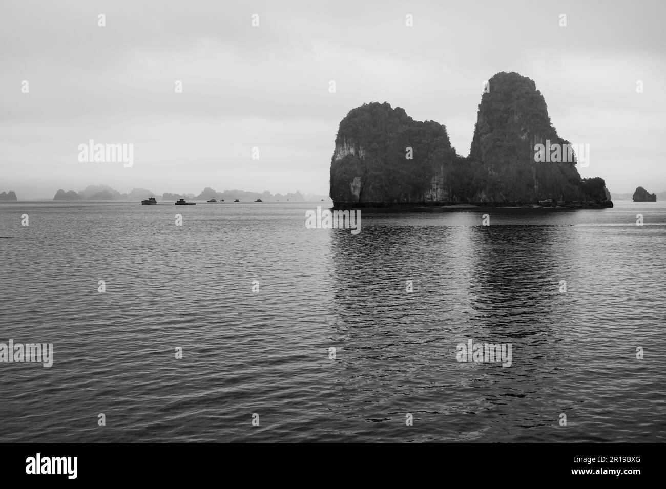 Chiatte che navigano tra le caratteristiche isole calcaree e isolette in Bai Tu Long Bay, Halong Bay, Vietnam. Foto Stock