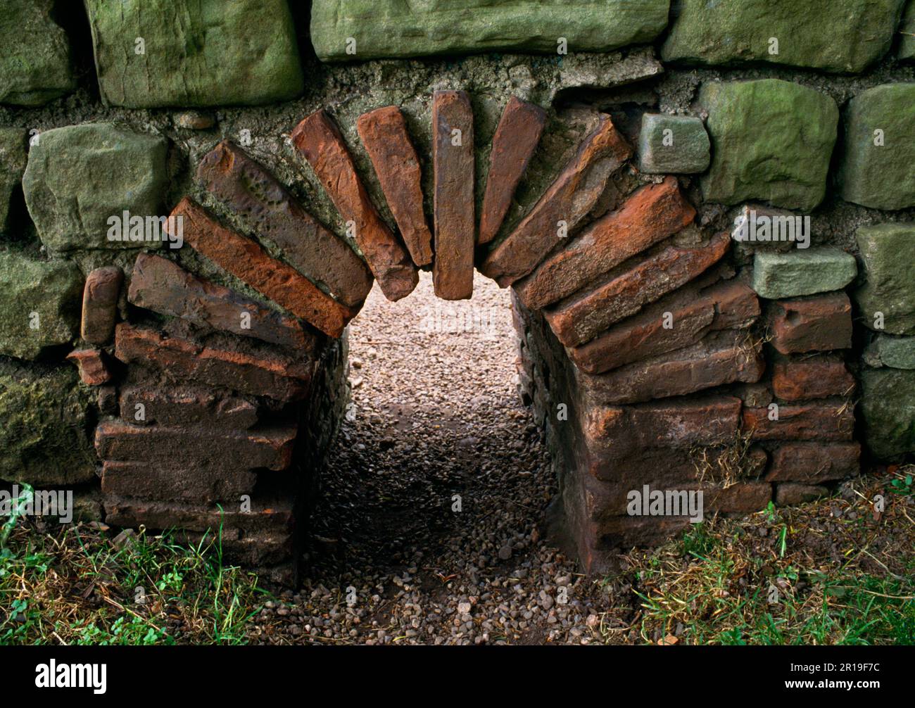 Una canna fumaria arcuata di piastrelle che convogliano aria calda da un forno a carbone esterno nella suite da bagno del comandante presso il forte romano di Chesters, il Muro di Adriano, Regno Unito. Foto Stock