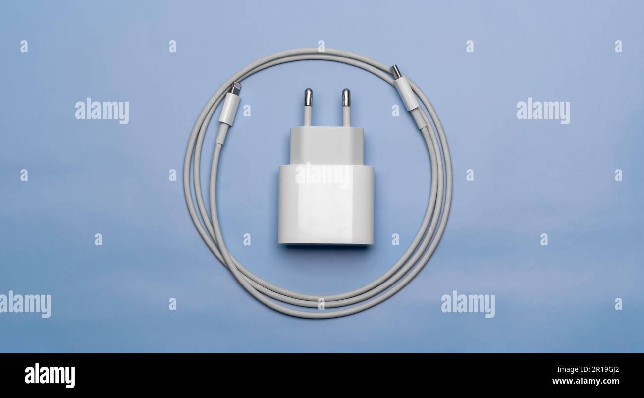 Caricabatterie per telefono cellulare con cavo avvolto su sfondo blu Foto Stock
