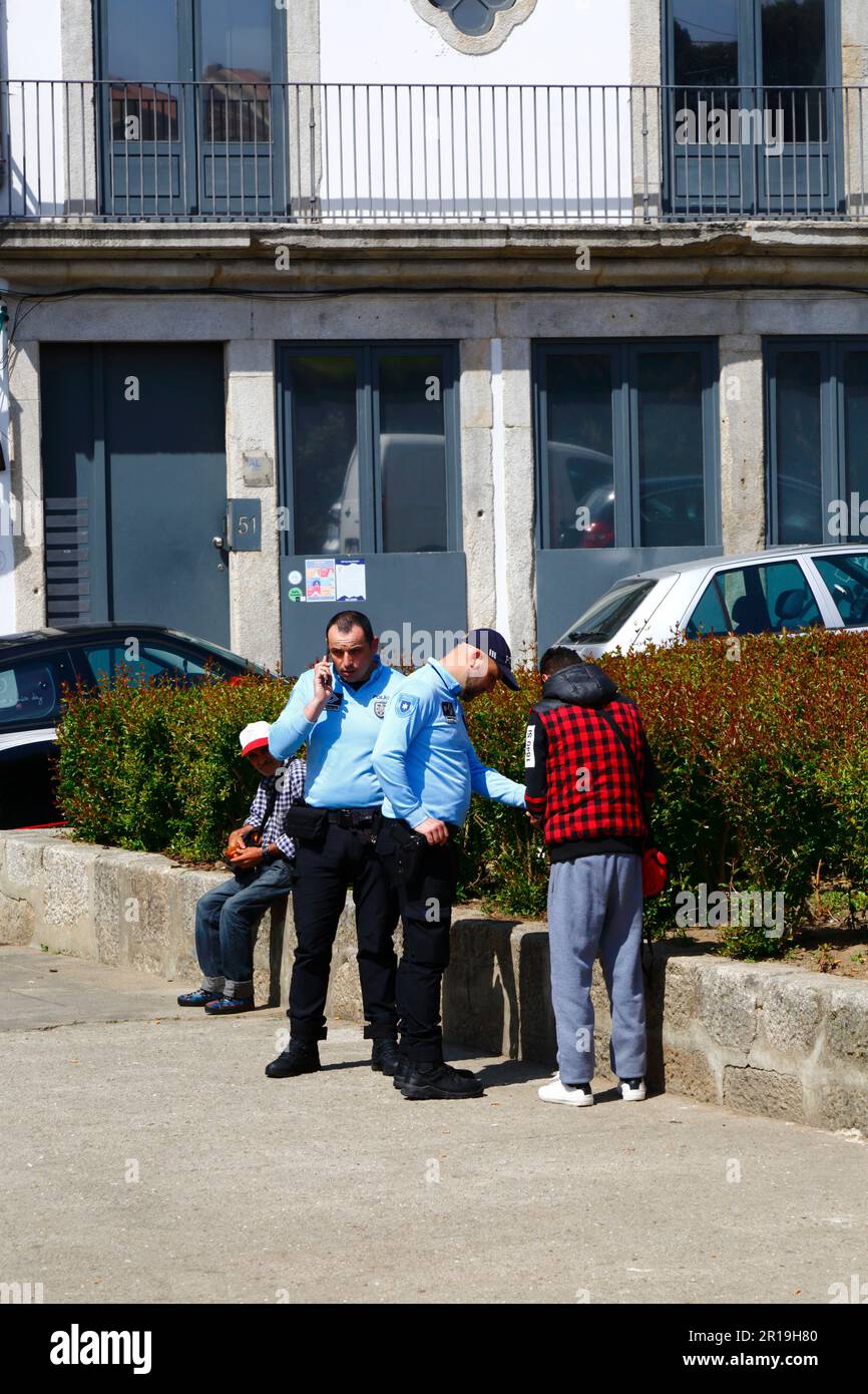Polizia di pubblica sicurezza portoghese che controlla i documenti di una persona seduta nella piazza a vicino al centro della città, Porto / Porto, Portogallo Foto Stock
