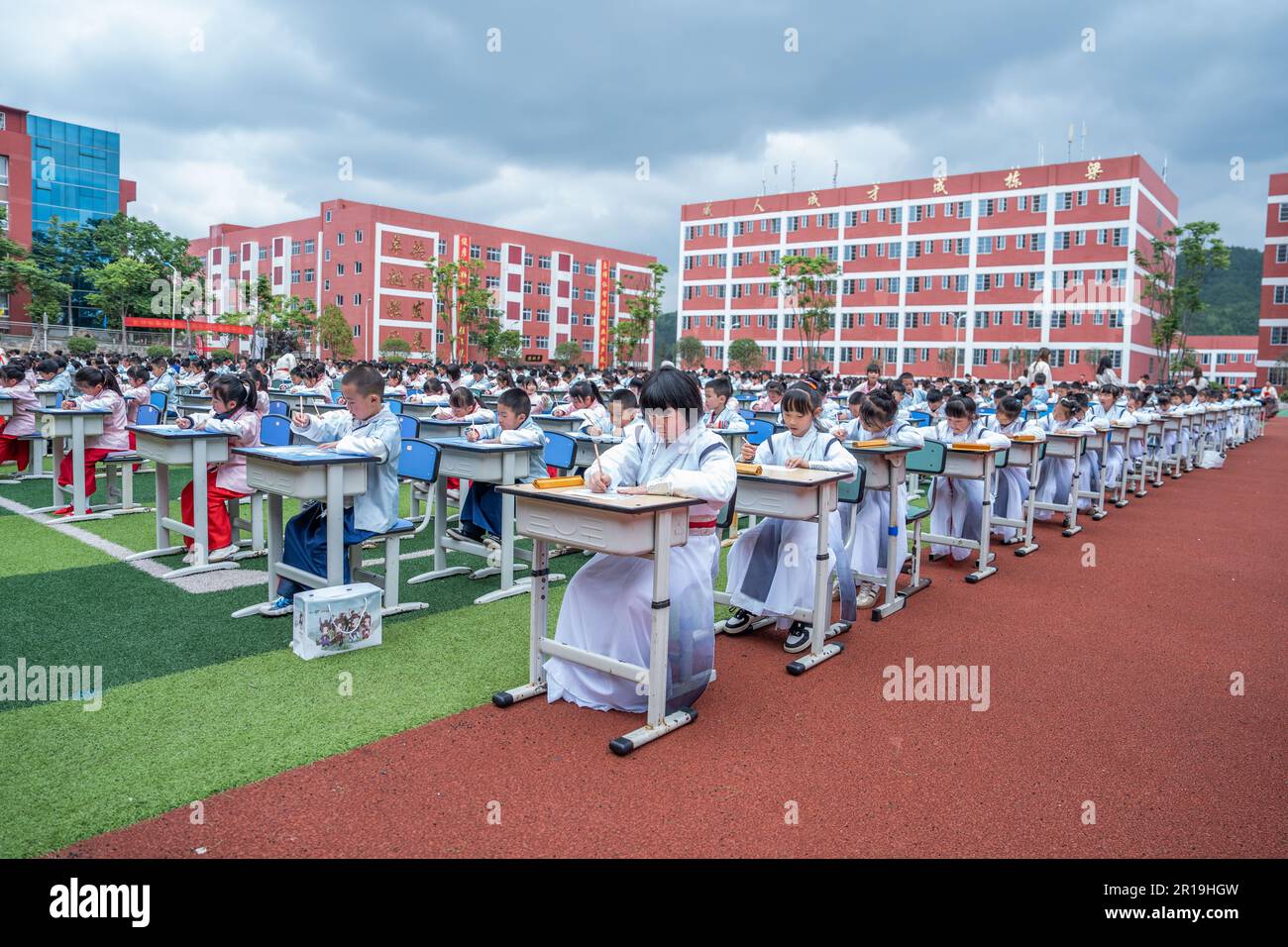 BIJIE, CINA - 12 MAGGIO 2023 - gli studenti partecipano ad un'attività di scrittura di antichi personaggi cinesi sul campo di gioco della Liangcai School di Bijie, provincia di Guizhou, Cina sudoccidentale, 12 maggio 2023. L'attività è svolta attraverso la mostra di Hanfu campo, antica etiquette esposizione, recita opere classiche, studi tradizionali cinesi mostra e scrivere antichi caratteri cinesi e altri collegamenti, guidando i bambini a sperimentare la lunga storia della cultura cinese nella recitazione e calligrafia, assorbire la ricca alimentazione dell'eccellente cultura nazionale. (Foto di Costfoto/NurPhoto) Foto Stock