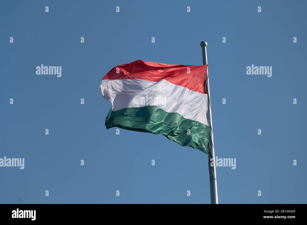 Bandiera nazionale dell'Ungheria che sventola da un'asta di bandiera contro un cielo blu Foto Stock