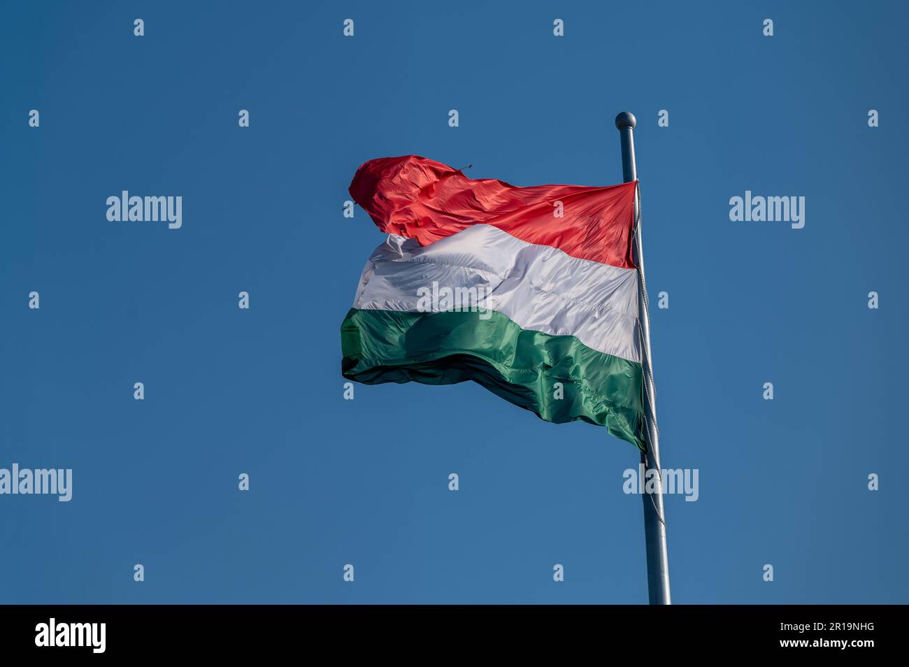 Bandiera nazionale dell'Ungheria che sventola da un'asta di bandiera contro un cielo blu Foto Stock